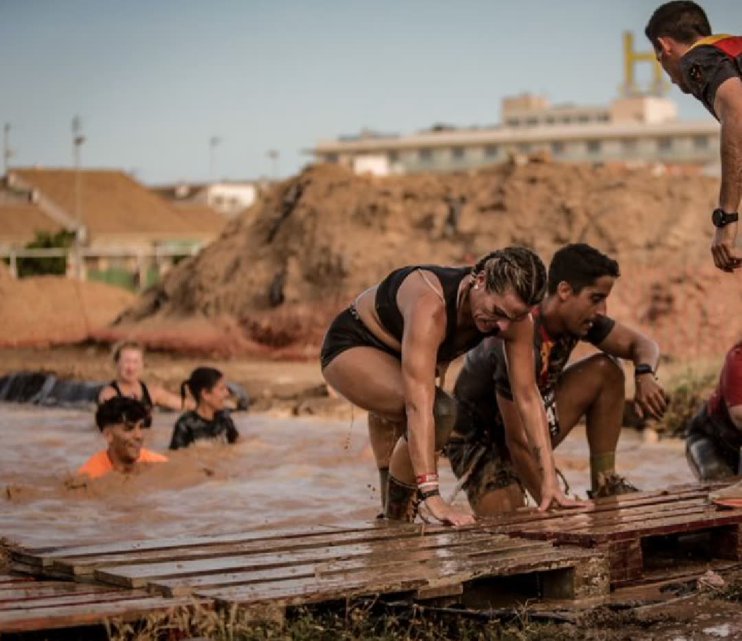 Corredores saliendo de una piscina de barro en una carrera de obstáculos